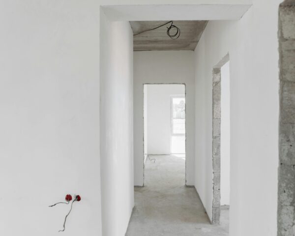 A minimalist view of an unfinished building interior with white walls and door frames.